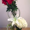 One dozen red roses grouped together with white hydrangeas and white oriental
