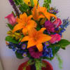 A colorful arrangement containing lilies, roses, bells of Ireland, gerberas, etc.. Suitable