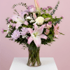 A fresh mix of pink lilies, roses, soft lavender blooms, and lush