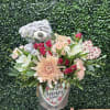 THIS ADORABLE BEAR ACCENTS MULTI COLORED BLOOMS IN A QUAINT TIN (TIN