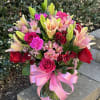 A pink and red bouquet of roses, lilies, carnations, spray roses, and