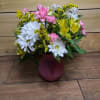A mix of spring blooms in a spring colored vase