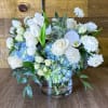 Beautiful round arrangement with a mixture of roses, blue hydrangeas, spray roses