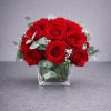 One dozen red roses arranged in a clear glass cube accented with