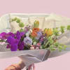 The arrangement includes various floral species such as purple orchids, lavender rose