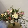 A lush garden-style bouquet featuring delicate white florals accented with gentle pink