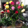 A cheerful arrangement contains one dozen long stem-colored roses in a cylinder