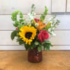 Hot pink roses and yellow sunflowers feature with fragrant white stock, bells