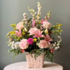 Brighten any occasion with this pink, yellow, and white floral basket, featuring