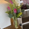 s petite arrangement features vibrant tulips and lush greens designed to bring