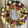 Multi color flowers, thoughtfully arranged in a large round standing Spay Wreath.