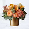 The Gilded Bouquet is a warm, refined floral arrangement featuring peach ranunculus