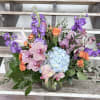 A lush statement arrangement featuring pre minimum Orchids, Hydrangea, Roses, and seasonal