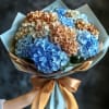 Bouquet of blue and tan hydrangeas wrapped in pale paper with a satin bow