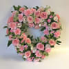 An 18" heart wreath with pink roses, white filler and pink carnations.