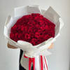 A bouquet of 100 fresh red roses, neatly wrapped in white paper.