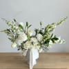 An arrangement of white flowers and greeneries, placed in a white vase.