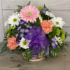 A basket of mixed blooms including daisies, gerberas daisies, carnations and buttons.