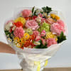 A round bouquet with yellow, coral, peach, pink, white, and green flowers