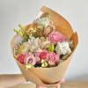A round bouquet with pink, ivory, and white flowers, wrapped in craft