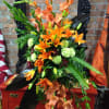Orange lillies, dark orange gladiolas, lime green carnations, aspidistra leaves highlighted by