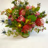 This long lasting arrangement features protea, pincushion, dianthus, wax flower, eucalyptus, thistles
