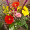 Cheery vase with orange gerberas, yellow daisies, pink carnations, waxflower and liatris.