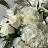 Close-up of ivory roses and white hydrangeas clustered in a lush bouquet