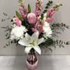 Pink and white flowers such as roses, snapdragons, mums, lilies, etc arranged
