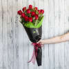 A dozen velvety red roses along with lush greenery and white accent