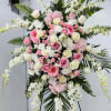 Artfully arranged pink and white florals create a captivating standing spray to
