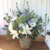 Tall white and purple mixed flower arrangement in a woven basket