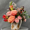 A charming floral mug arrangement featuring soft peach and blush roses, delicate