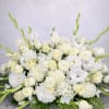 A graceful all-white sympathy arrangement designed with white roses, ranunculus, chrysanthemums, gladiolus