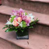 Compact vase arrangement with roses, orchids, lilies and hydrangea. 