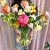 Mixed bouquet of tulips and daffodils in a clear glass vase