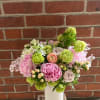 Pink and green floral arrangement in a white vase