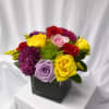 A cheerful and vibrant floral arrangement designed in a modern glass cube.