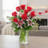 Arrangement of red roses and pink lilies in a clear glass vase on a table