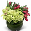 Pink tulips and green orchids in a dark glass vase with pale green hydrangeas