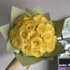 A radiant hand-tied bouquet of sunny yellow roses, wrapped in soft green