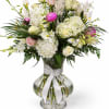 White and pink floral arrangement in a clear glass vase with a white ribbon