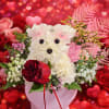 Heart-themed flower arrangement with a teddy bear face and red rose
