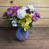 A mix of carnations, daises, and alstroemeria in a simple purple vase.