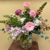 Clear vase of spring florals in shades of pink.