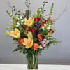 Mixed bouquet of lilies, roses, and snapdragons in a glass vase