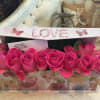Pink roses arranged in a floral gift box with a LOVE lid