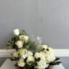 White roses and hydrangeas arranged around a clear glass vase
