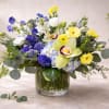 A fresh and vibrant spring arrangement featuring soft yellow blooms, blue hyacinths