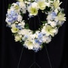 Heart-shaped floral wreath with white and pale blue flowers on a stand